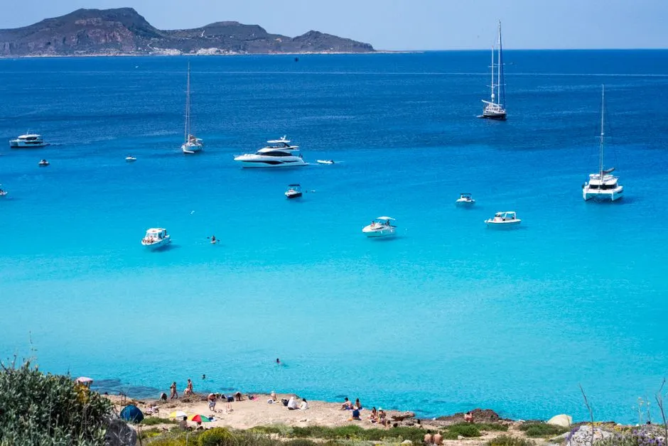 Turquoise water and anchored boats off a rocky cove on the island of Favignana, Sicily