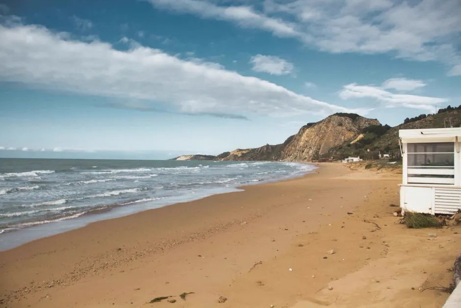 A quiet sandy beach on Sicily's southern coast near Eraclea Minoa, with pale cliffs in the distance