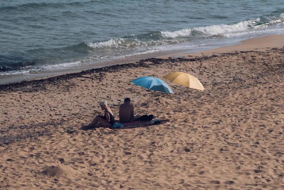 A wide, gently sloping sandy beach with umbrellas on Sicily's south coast, near Marina di Ragusa