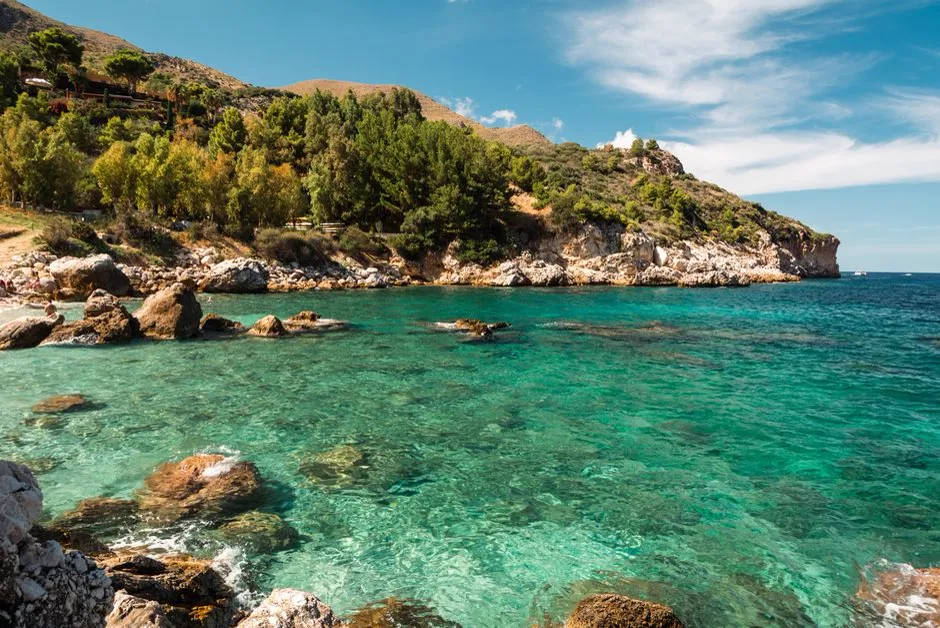 A turquoise cove inside the Riserva dello Zingaro nature reserve, framed by rocky cliffs and pine trees