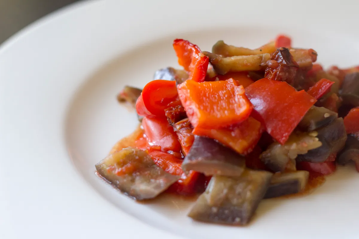 Catania-style caponata with eggplant and red bell pepper pieces in a tomato sauce.