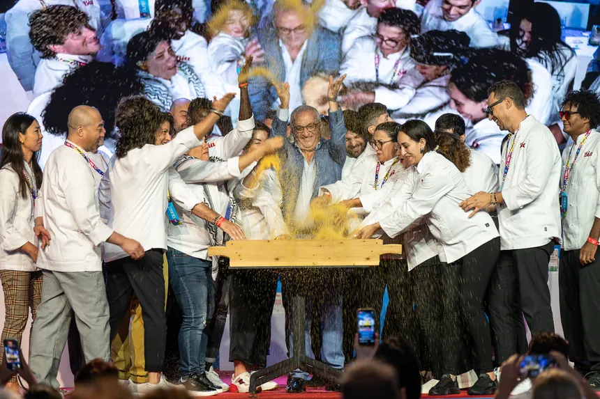 Chefs in white jackets throwing semolina into the air together at the opening of the Cous Cous Fest in San Vito Lo Capo.
