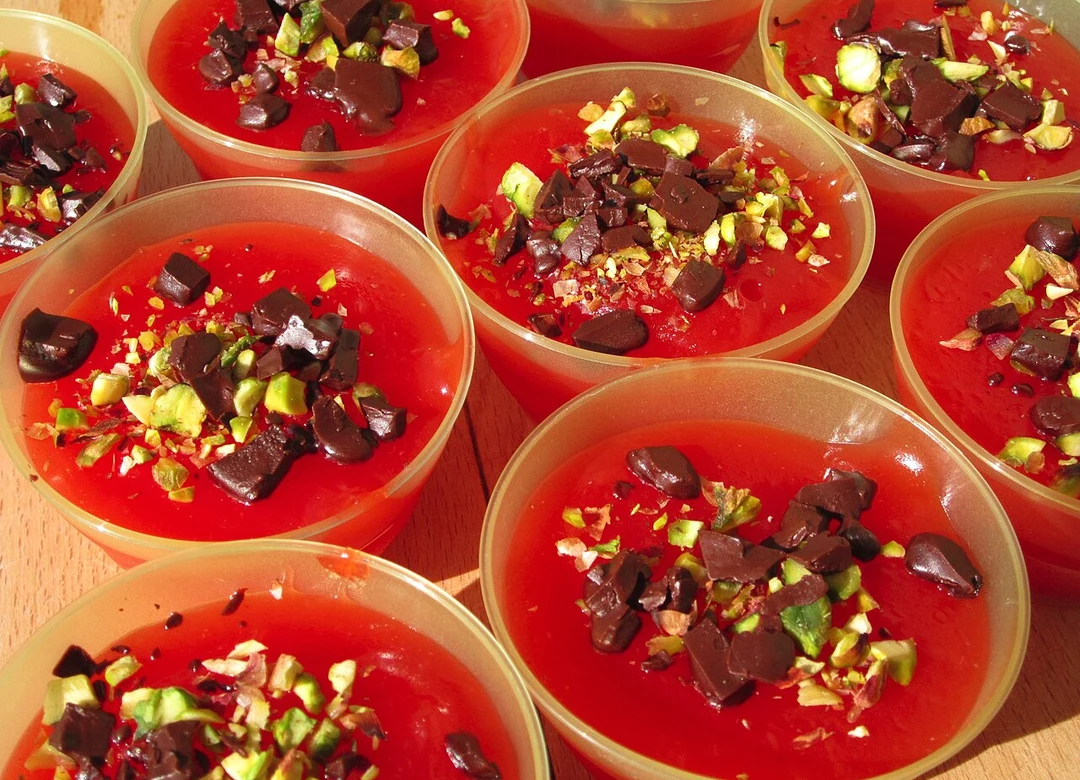 Several bowls of red Sicilian gelo di melone, topped with roughly chopped dark chocolate and pistachios.