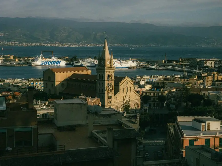 Aerial view of Messina Cathedral with harbor and ferries in the background.