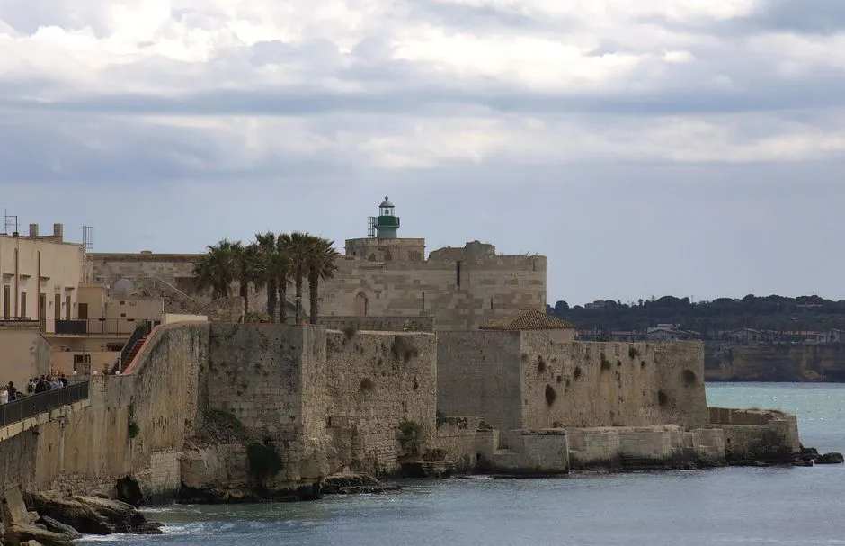 Historic limestone walls and lighthouse on Ortigia Island in Siracusa, Sicily.