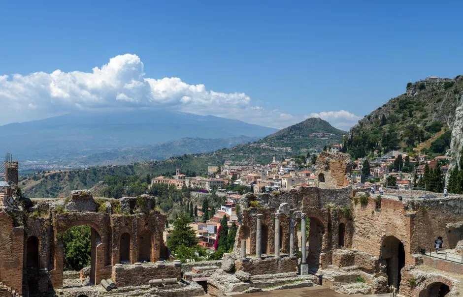 Explore the awe-inspiring ruins of the Ancient Theatre of Taormina, Sicily with Mount Etna in the background.