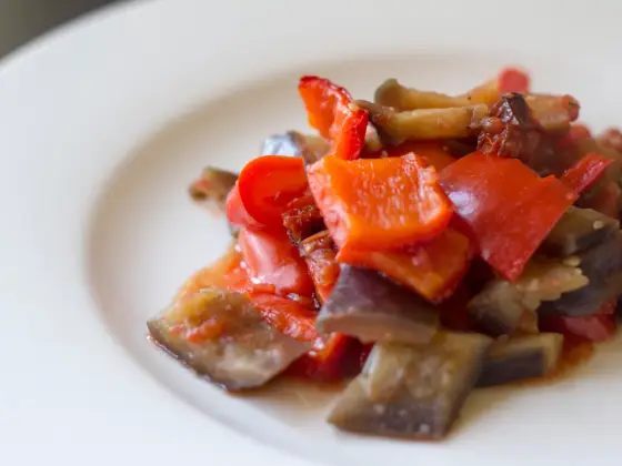 Catania-style caponata with eggplant and red bell pepper pieces in a tomato sauce.