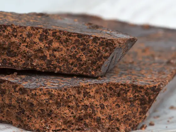 Two broken bars of Cioccolato di Modica showing a visibly grainy, matte fracture with fine sugar crystals.