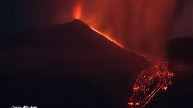 A nighttime lava fountain and lava flows on Mount Etna, the sky lit red by the volcanic glow.