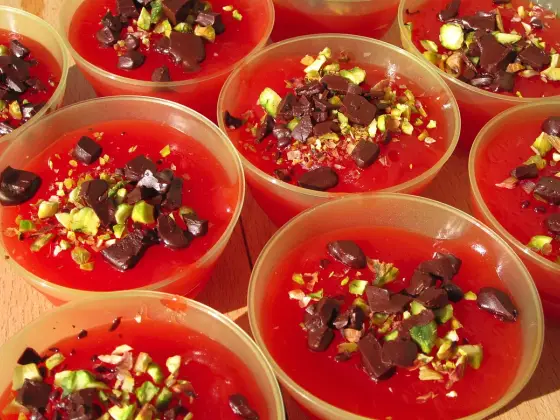 Several bowls of red Sicilian gelo di melone, topped with roughly chopped dark chocolate and pistachios.