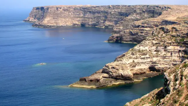 The dramatic limestone cliffs of Lampedusa's north-eastern coast, dropping straight into deep blue Mediterranean water.