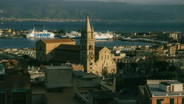 Aerial view of Messina Cathedral with harbor and ferries in the background.