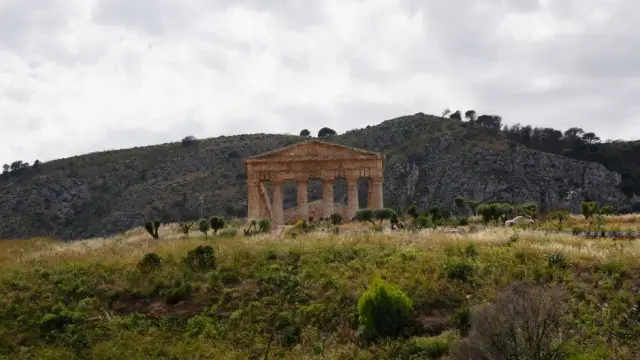The isolated Doric temple of Segesta standing alone on a grassy hilltop, surrounded by hills, near Trapani, Sicily.