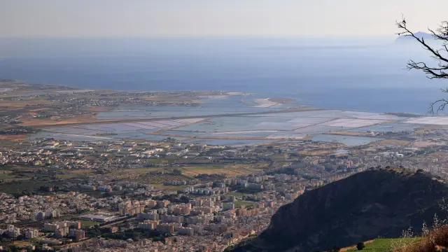 Aerial view of Trapani's coastline and salt pans in Sicily, seen from the hills above, with the sea in the background.